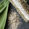 A close-up shot of spices spilled from a glass container next to green leaves. Produktbild-Vorschau