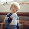 A young child drinks from a sippy cup. Voir les images du produit