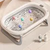 A foldable baby bathtub filled with water and colorful balls, with two bottles of soap or lotion on the side. Produktbild-Vorschau