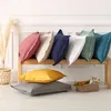 A collection of pillows in various colors arranged on a wooden bench and on the floor. Náhled obrázku produktu