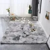 A fluffy gray rug is laid out on a tiled floor in a room with sheer curtains and a small table with decorative items. Podgląd zdjęcia produktu
