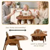 A family is interacting with a baby in a high chair in a kitchen setting. Produktbild-Vorschau