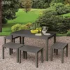 A garden table and benches set in a natural outdoor setting with lush greenery in the background. Náhled obrázku produktu