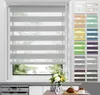 A window with a gray roller blind and a collage of different colored roller blind samples on the right. A vase of flowers and a pastry are on a table in the foreground. Produktbild-Vorschau