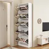 A tall, white shoe cabinet with multiple angled shelves filled with shoes, placed next to a doorway in a hallway. Produktbild-Vorschau