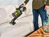 A person is using a cordless vacuum cleaner to clean a sofa. Produktbild-Vorschau