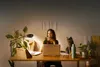 A woman is working at a desk with a laptop and a cat is sitting next to her. Produktbild-Vorschau