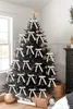 A decorated Christmas tree with beige bows and gold ornaments, set in a room with gifts underneath. Voir les images du produit