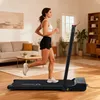A woman is running on a treadmill in a living room. Produktbild-Vorschau