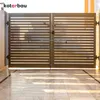 A pair of black metal gates with horizontal slats, viewed from the front, with sunlight casting shadows on the marble floor in front of them. Náhled obrázku produktu