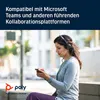 A woman wearing a headset is looking at her phone while sitting outdoors. Produktbild-Vorschau