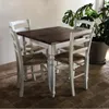 A dining set with chairs around a table, placed on a tiled floor with a plant in the background. Produktbild-Vorschau