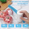 A hand is holding a white vacuum sealing machine next to a bag of tomatoes and an avocado on a wooden board. Produktbild-Vorschau