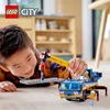 A young boy is playing with a LEGO City construction crane toy on the floor. Podgląd zdjęcia produktu