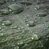 Close-up of water droplets on a green surface, likely a tarp or fabric. Podgląd zdjęcia produktu