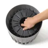 A hand is shown inserting something into a round, ribbed container. Náhled obrázku produktu