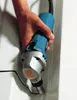 A hand is holding a power tool and using it to cut a black wire or cable inside a white structure. Podgląd zdjęcia produktu