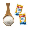 A wooden spoon filled with salt next to two small packets of iodized salt. Náhled obrázku produktu