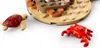 A close-up view of LEGO bricks forming a beach scene, with a small red crab and a dark red turtle. Podgląd zdjęcia produktu