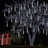 A tree decorated with white icicle lights at night, with a house in the background also decorated with lights. Produktbild-Vorschau