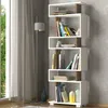 A modern white and walnut bookshelf filled with books and decorative items, placed next to a window with sheer curtains and a floor lamp. Produktbild-Vorschau