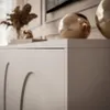 A close-up view of a white TV stand with decorative gold spheres on top. Produktbild-Vorschau