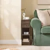 A narrow wooden nightstand with a drawer and shelves is placed next to a green sofa in a living room. Anteprima dell’immagine prodotto