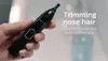 A hand holding a black Philips nose trimmer with text overlay. Podgląd zdjęcia produktu