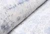 A close-up view of a rolled-up rug with a textured surface and a pattern of cream and blue. The rug is partially unrolled, showing the soft fibers. Náhled obrázku produktu