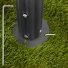 A close-up view of a black metal pole with a base plate on artificial grass, with a silver Allen wrench and a metal pin nearby. Náhled obrázku produktu