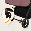 Close-up view of a stroller wheel and brake mechanism, with an inset circle highlighting a spring and a crossed-out wrench icon. Produktbild-Vorschau