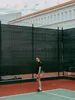 A young man stands on a tennis court, holding a tennis racket. Produktbild-Vorschau