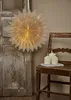 A paper star lantern hangs next to an old wooden door, with a rustic wooden chair holding three lit candles on a book. Podgląd zdjęcia produktu