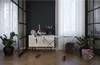 An ironing board with an iron and laundry basket in a room with plants and curtains. Podgląd zdjęcia produktu