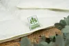 A close-up of a white duvet with a green trim and a green label. Produktbild-Vorschau