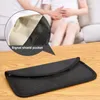 A black signal-blocking pouch is placed on a wooden table in front of two people sitting on a couch. A close-up inset highlights the pouch's interior and the text 'Signal shield pocket'. Produktbild-Vorschau