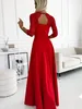 A woman is wearing a red dress in a room with a sofa and a table. Produktbild-Vorschau