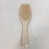 A gold and beige hairbrush is placed on a white and gray marbled surface. Anteprima dell’immagine prodotto