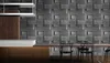 A dining area with a textured graphite brick wall, a wooden table, and chairs. Náhled obrázku produktu