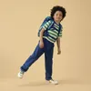 A young boy wearing a backpack and a striped t-shirt is posing against a plain background. Voir les images du produit