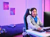A person wearing a headset is playing a video game in a room with purple and pink lighting. Anteprima dell’immagine prodotto