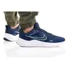 A person wearing blue Nike Downshifter 12 shoes and green pants, shown from the side against a white background. Anteprima dell’immagine prodotto