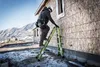 A construction worker is using a green multi-purpose ladder against the side of a house under construction. Podgląd zdjęcia produktu