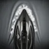 A close-up, top-down view of a black steam iron being used on a gray fabric, with steam rising from the iron's soleplate. Produktbild-Vorschau