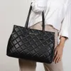 A person is holding a black quilted tote bag. Produktbild-Vorschau