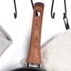 A close-up shot of a frying pan handle and part of the pan, hanging on hooks. Náhled obrázku produktu