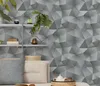 A shelf with decorative items and pillows in front of a geometric patterned wall. Produktbild-Vorschau
