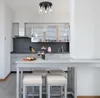 A modern kitchen with a bar island in the foreground, set for a meal with wine and food. Anteprima dell’immagine prodotto