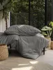 A bedding set is displayed on a bed with plants in the background. Produktbild-Vorschau