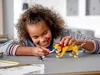 A young girl is playing with a LEGO lion toy. Náhled obrázku produktu